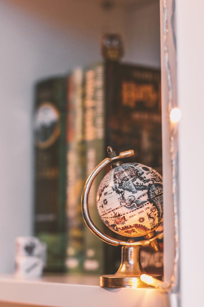 pexels photo 1004783 A cozy bookshelf featuring a vintage globe and warm string lights, creating a nostalgic atmosphere.