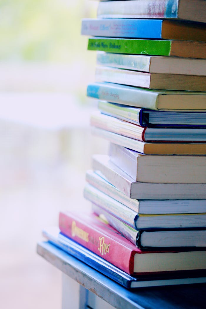 pexels photo 1148399 A tall stack of colorful hardcover books on a table indoors, perfect for library-themed concepts.