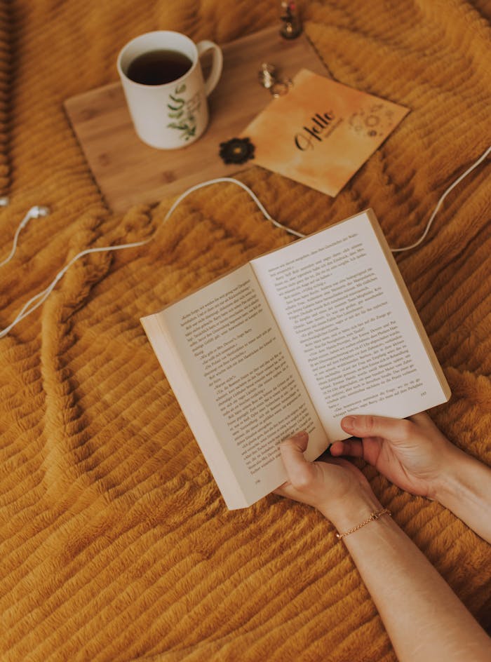 pexels photo 3563625 A person enjoying a relaxing reading session with a cup of coffee on a cozy bedspread.